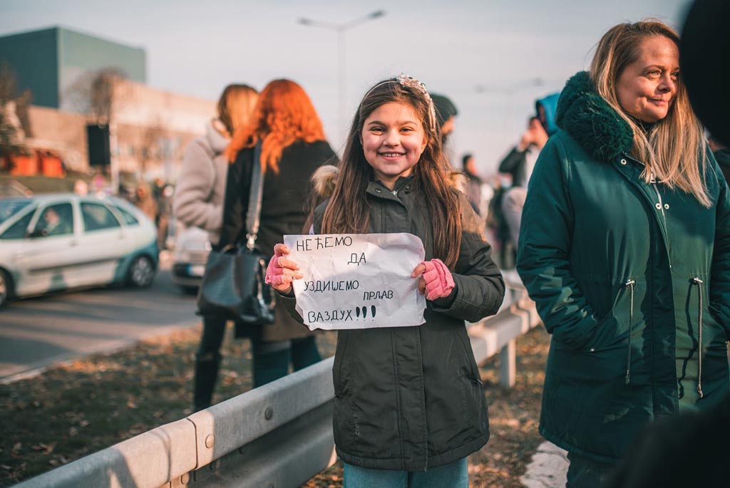 Фотографија од девојче што држи транспарент „не сакаме да дишеме загаден воздух“