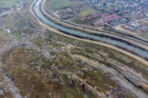 Фотографија од воздух од реката Вардар, на едната страна има дива депонија, а на другата страна населба со куќи.