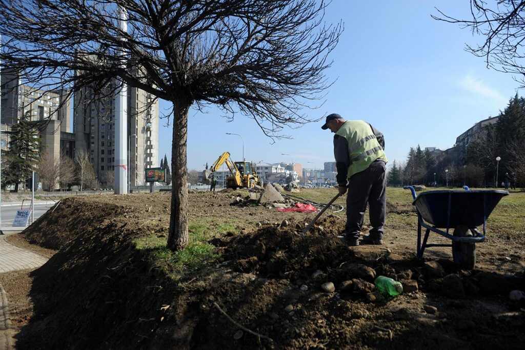 Фотографија од човек кој копа и ја уредува зелената површина во близина на студентскиот дом Гоце Делчев.