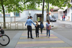 Фотографија од локален полицаец во Тирана кој помага на дечиња безбедно да преминат улица на пешачки премин.