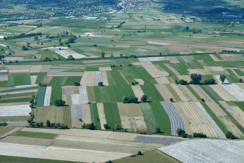 Фотографија од дрон на која се гледаат земјоделски површини во далечината.